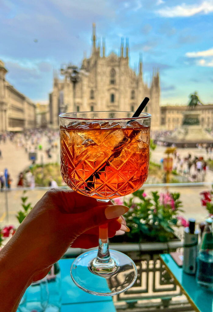 closeup of aperol spritze in front of the duomo