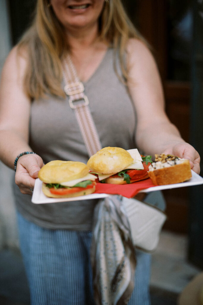 woman holding plate of Italian sandwiches