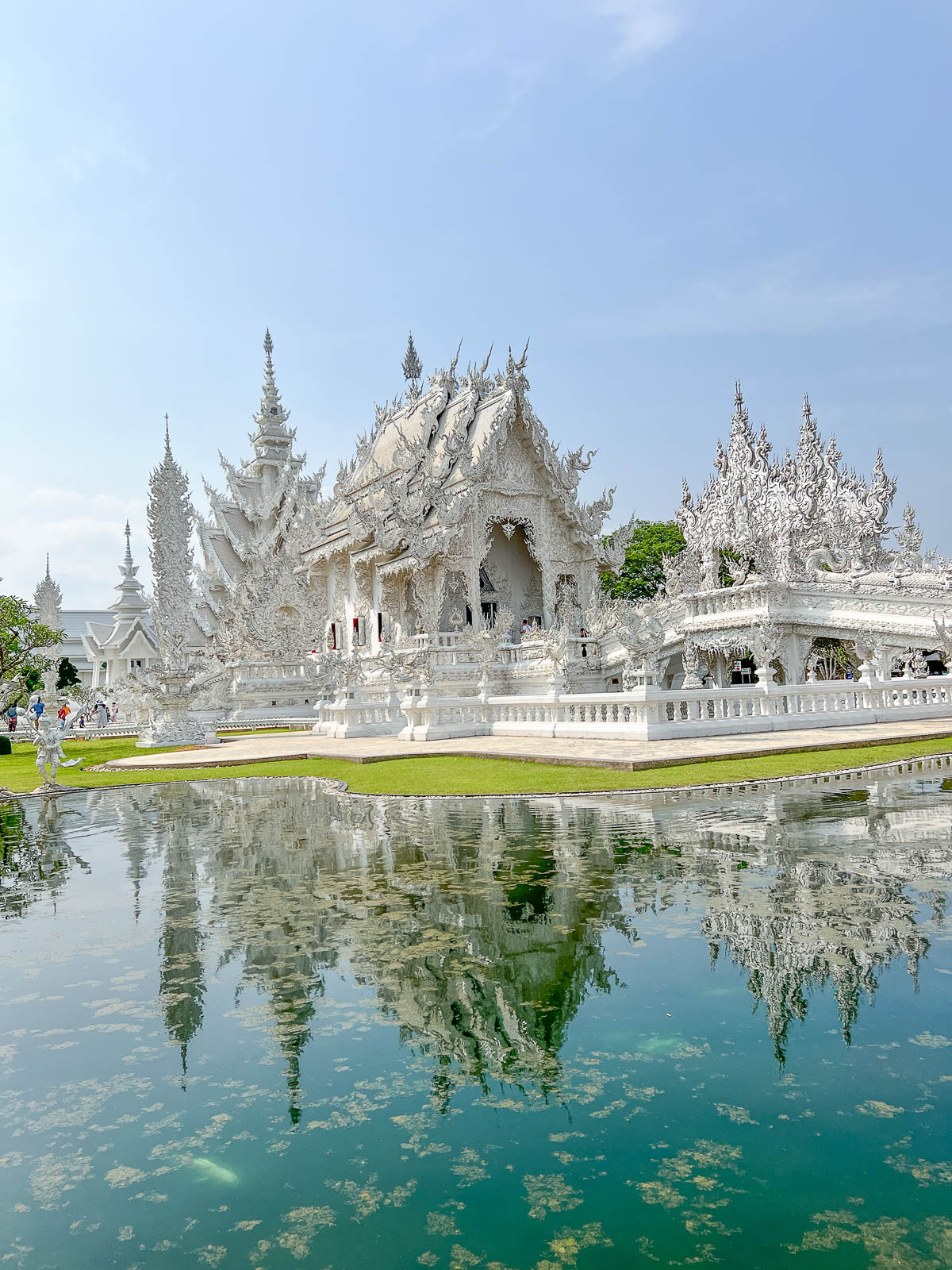 A white temple reflected in a pond in northern Thailand