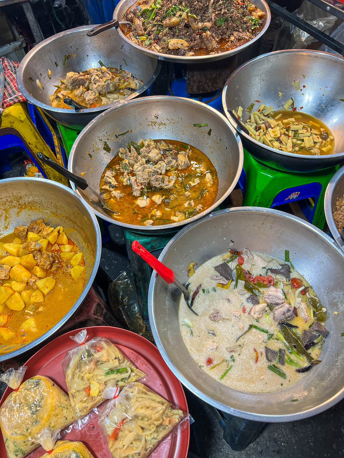 Metal bowls of Thai curries at a market stall