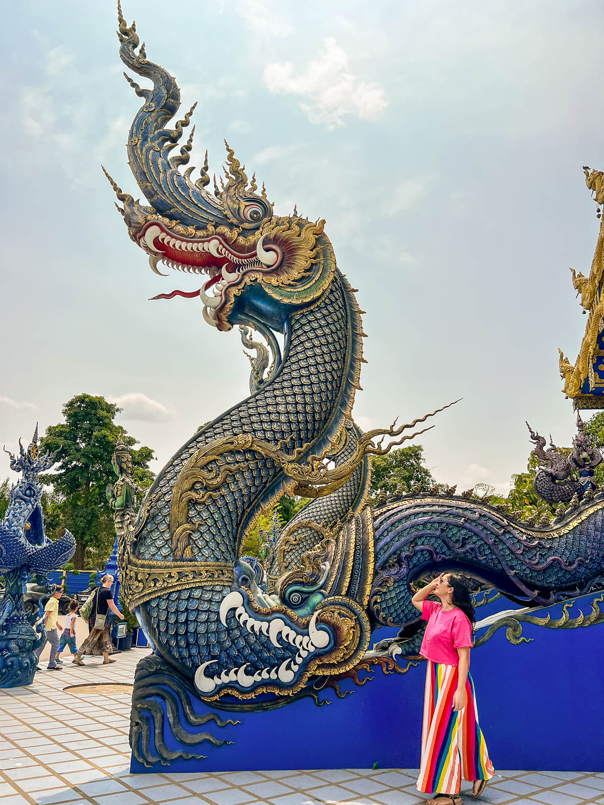 A blue dragon sculpture beside a temple staircase in Thailand