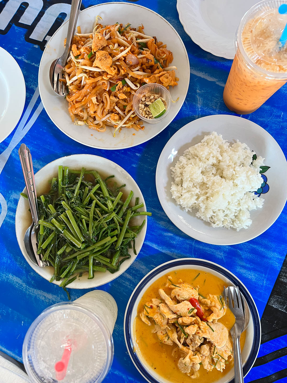 Plates of Thai dishes on a blue tablecloth