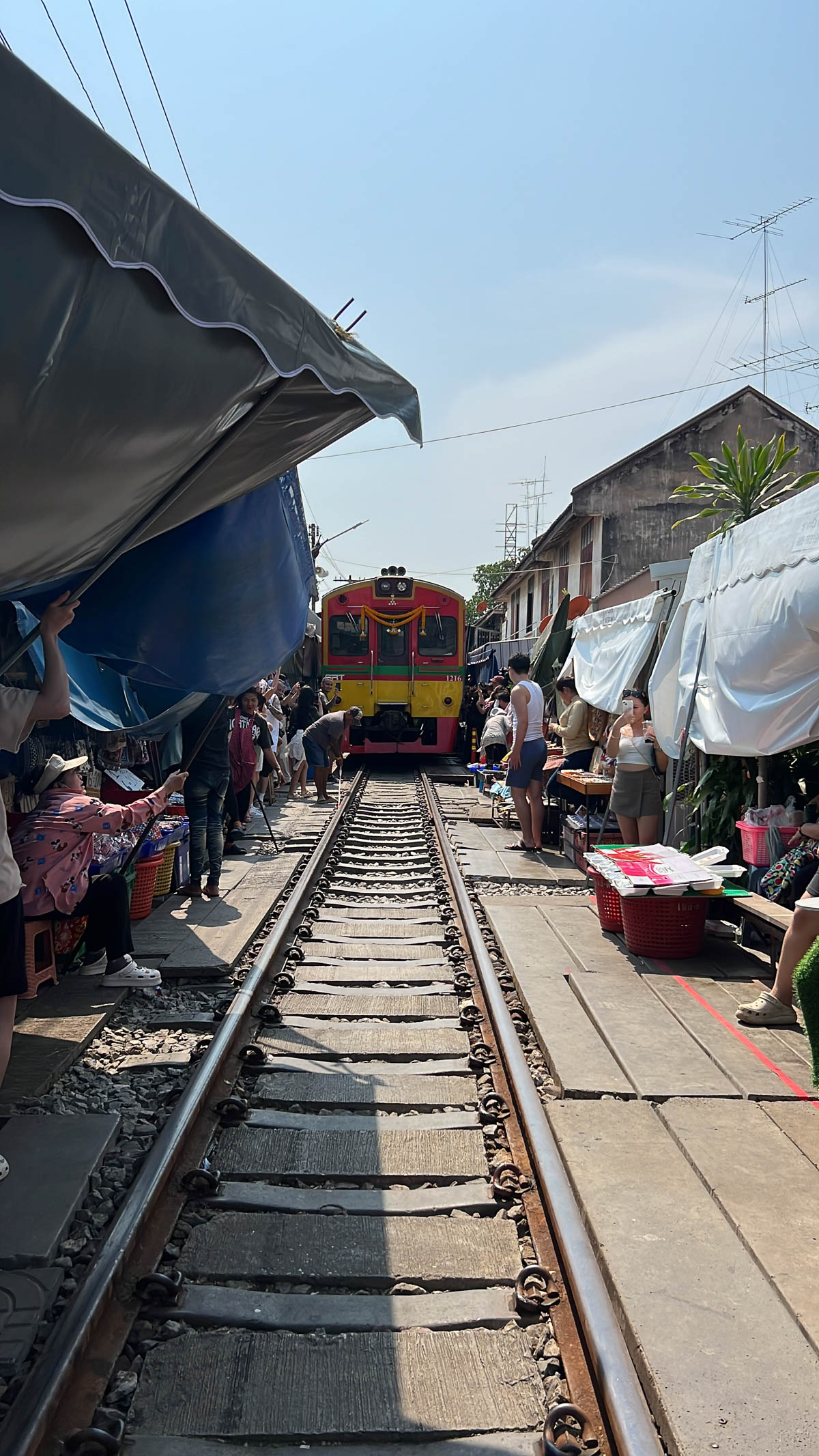 A train passing through a market built along the railway tracks in Thailand
