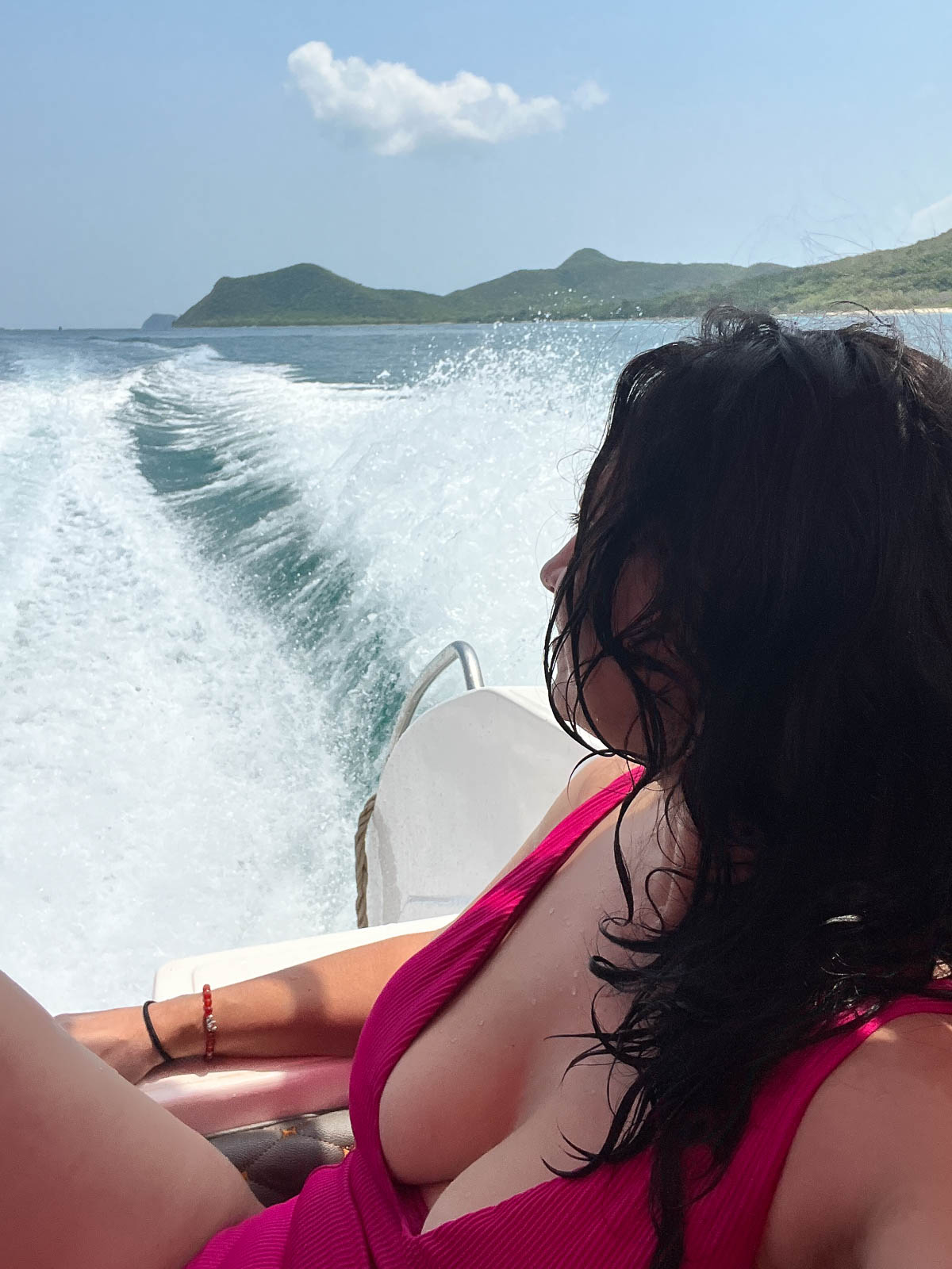 A traveler watching the wake from the back of a speedboat in Thailand