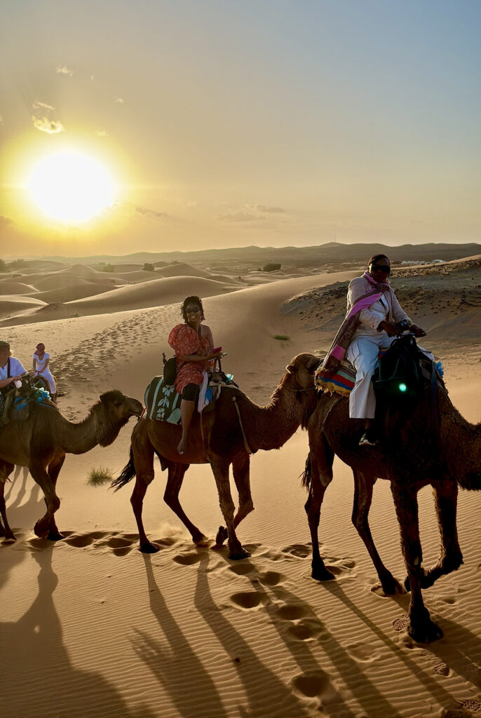 Women on camels walking through the desert.