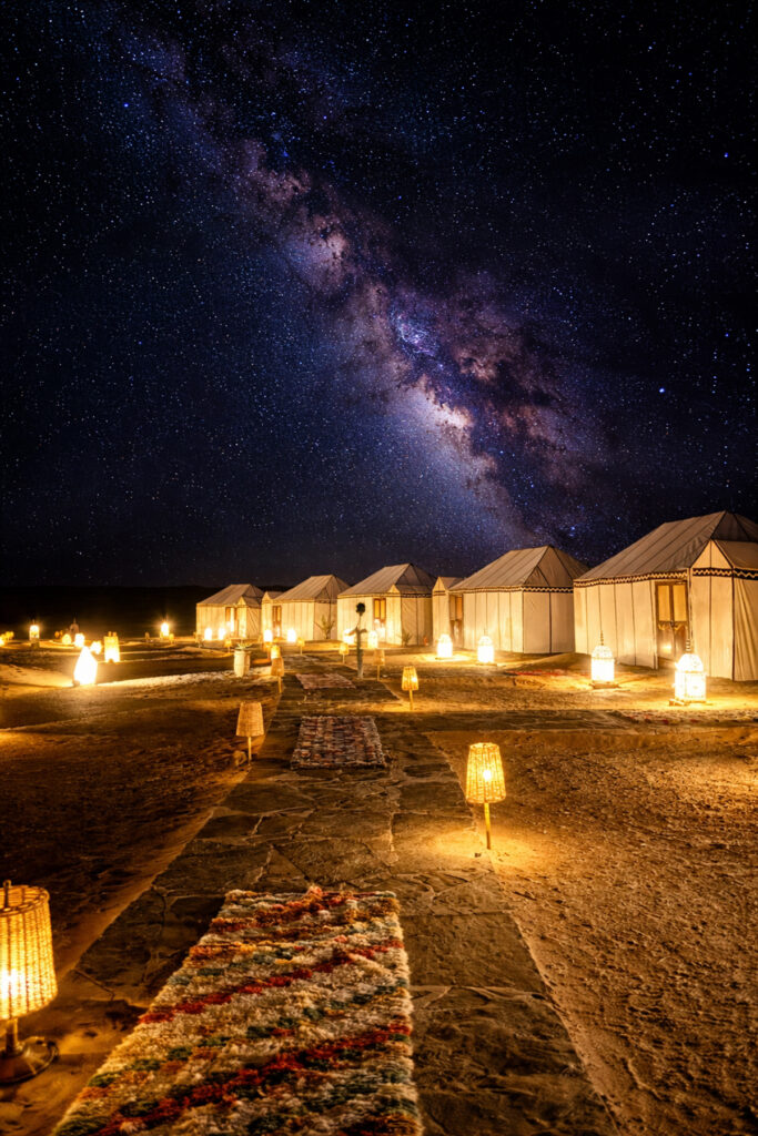 Tents glowing with lights under a star filled night sky.