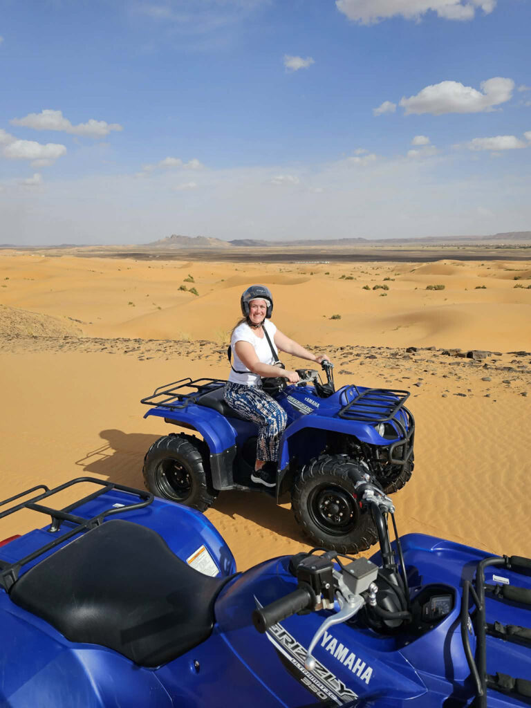 Woman sitting on a blue quad in the sahara desert.