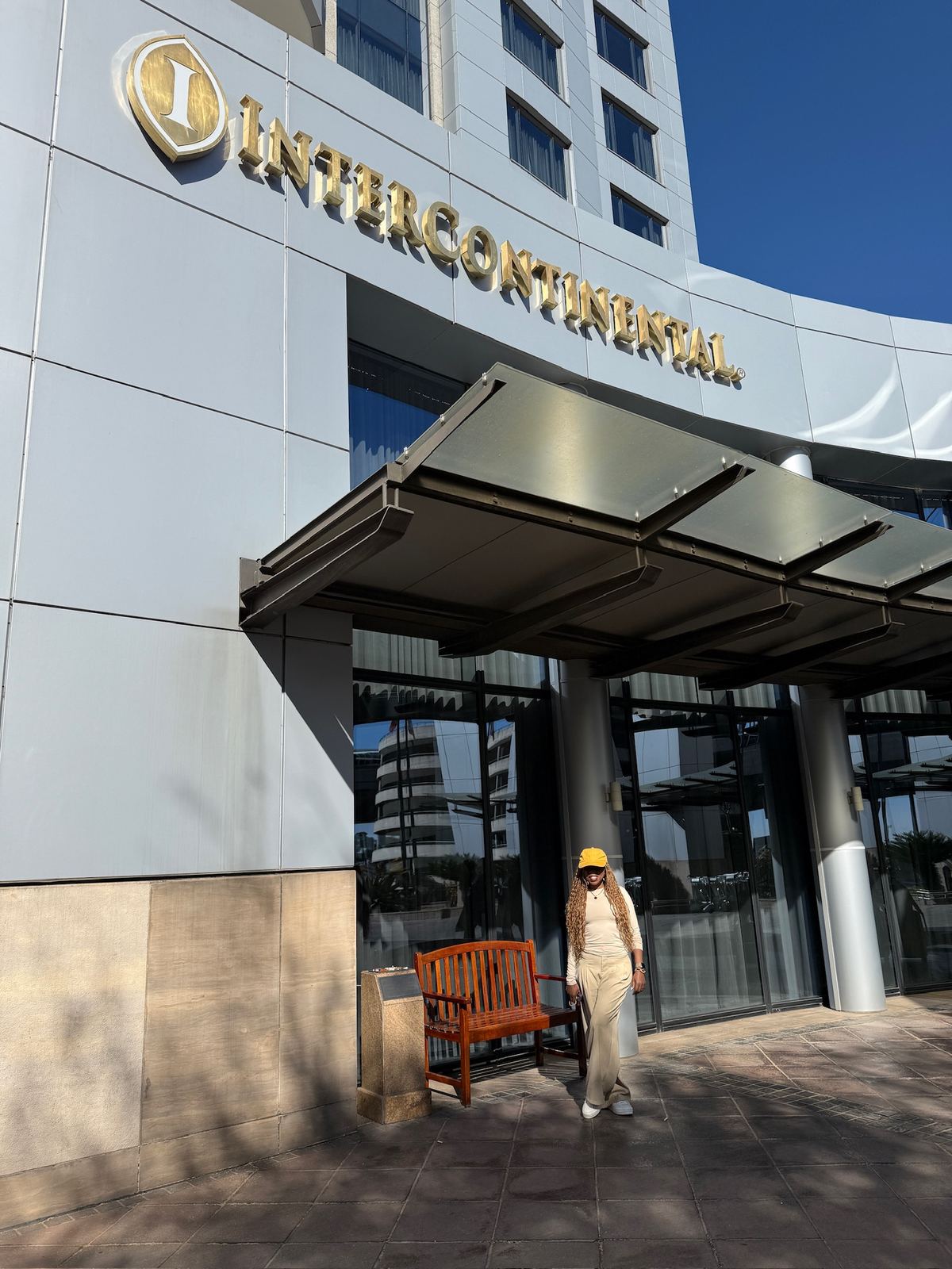 A woman in a yellow cap standing outside the entrance of the InterContinental hotel