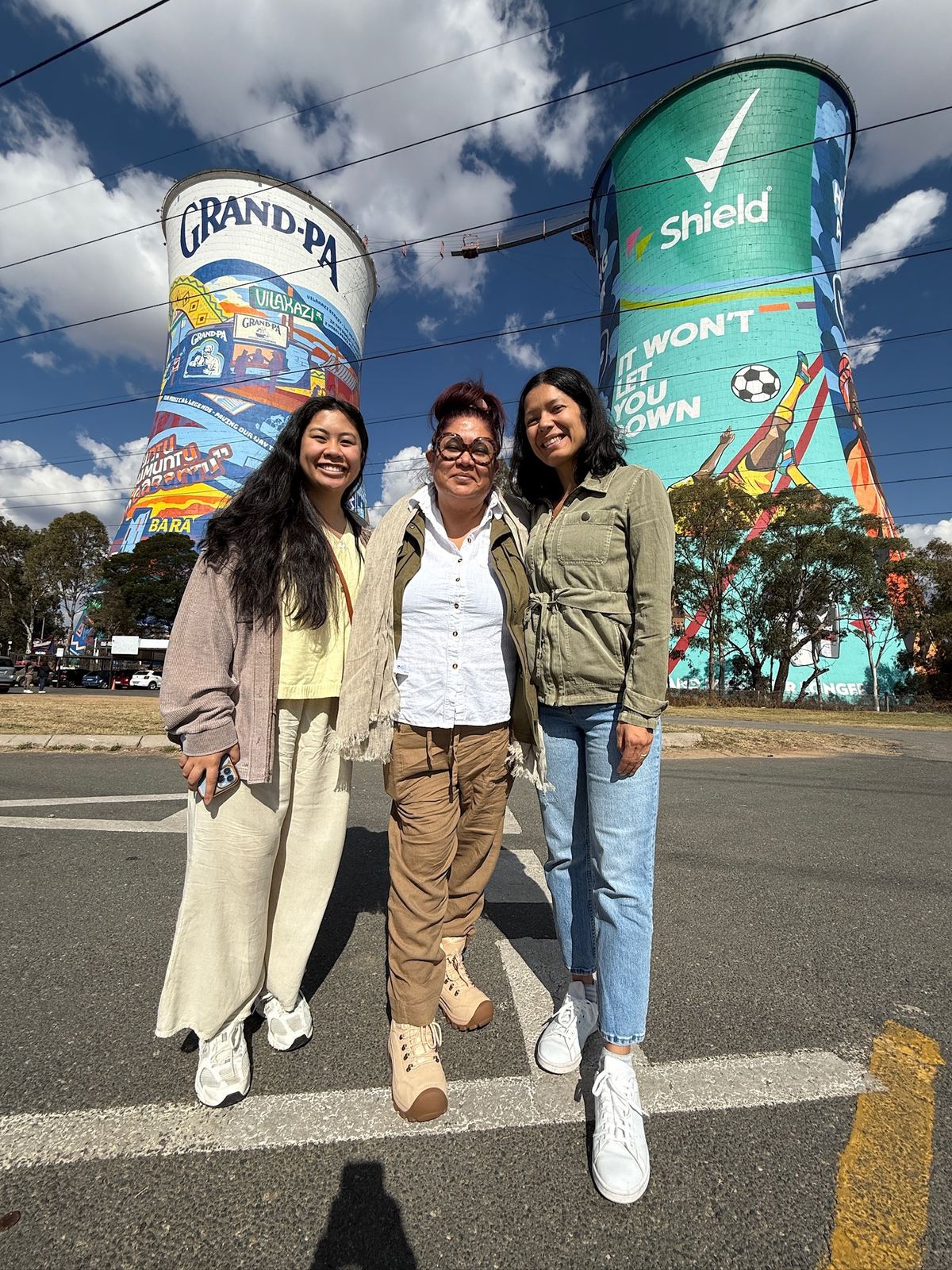Three women standing in front of the painted Orlando Towers in Soweto