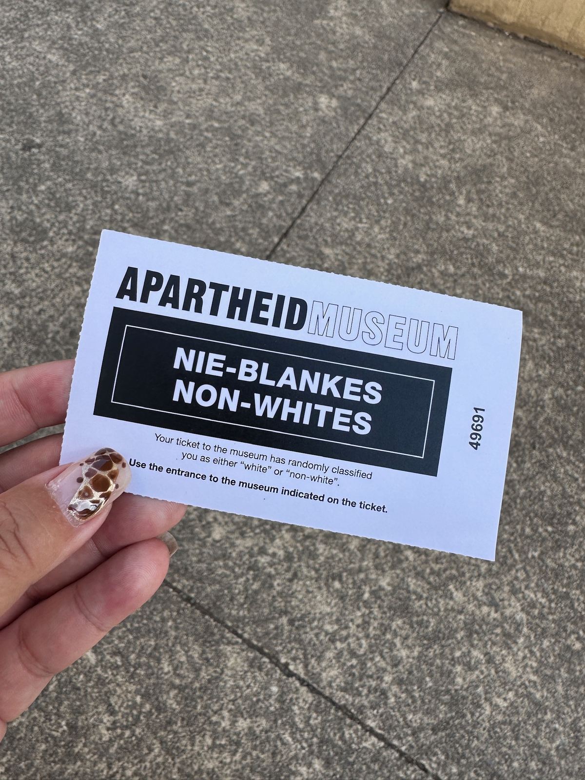 A hand holding an Apartheid Museum ticket stamped Non-Whites
