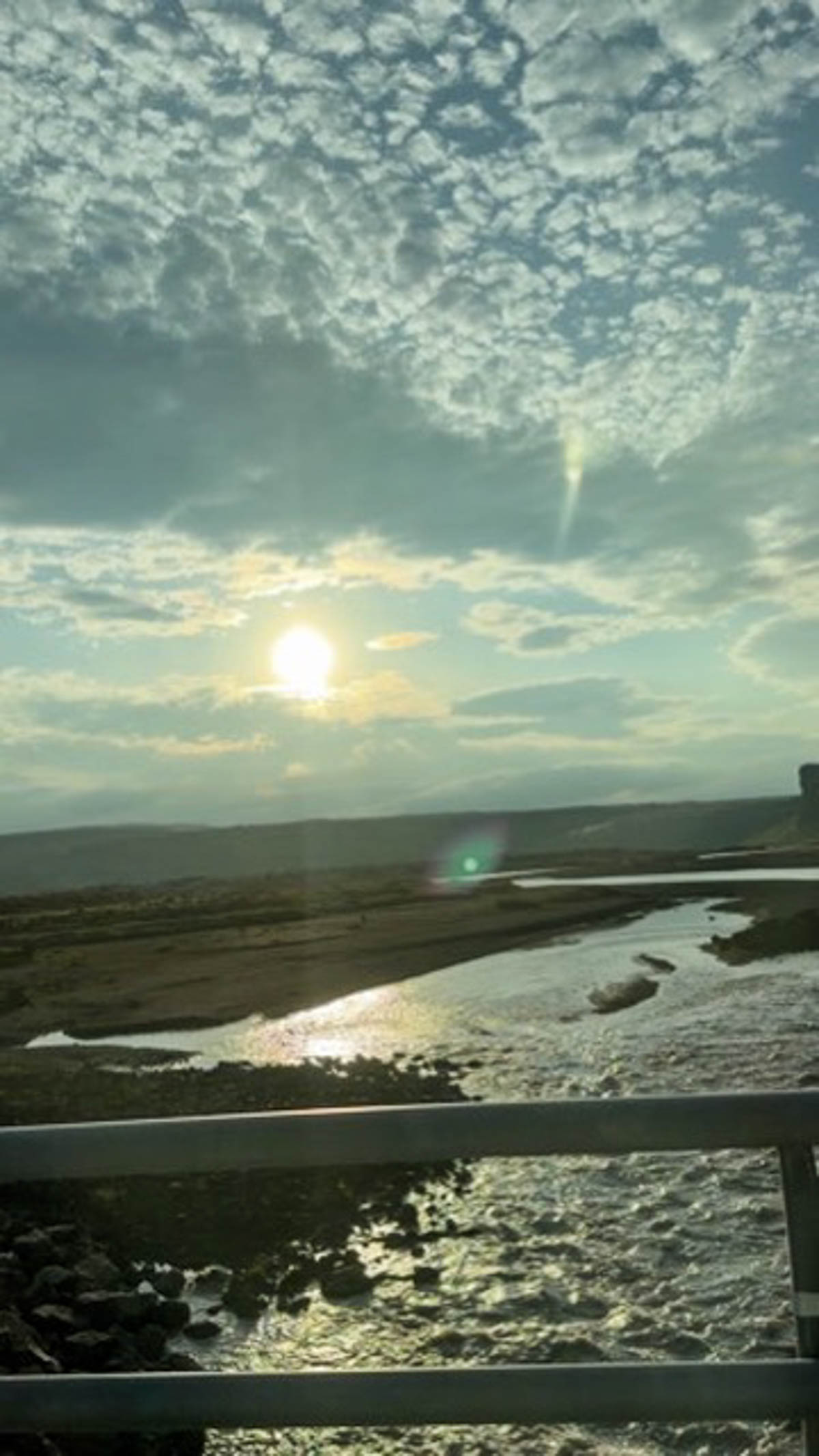 The sun low behind clouds over the water in Iceland