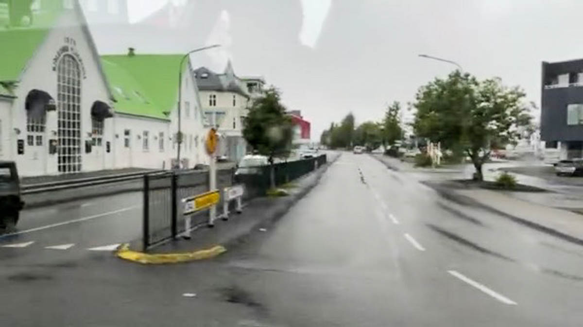 A rainy street in Reykjavík with a green-roofed building