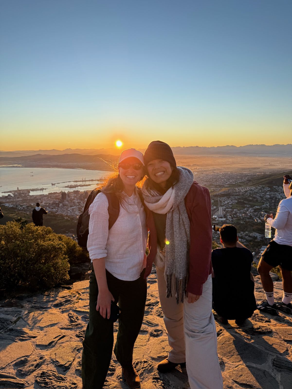 Two women on the summit of Lion's Head at sunrise with Cape Town below