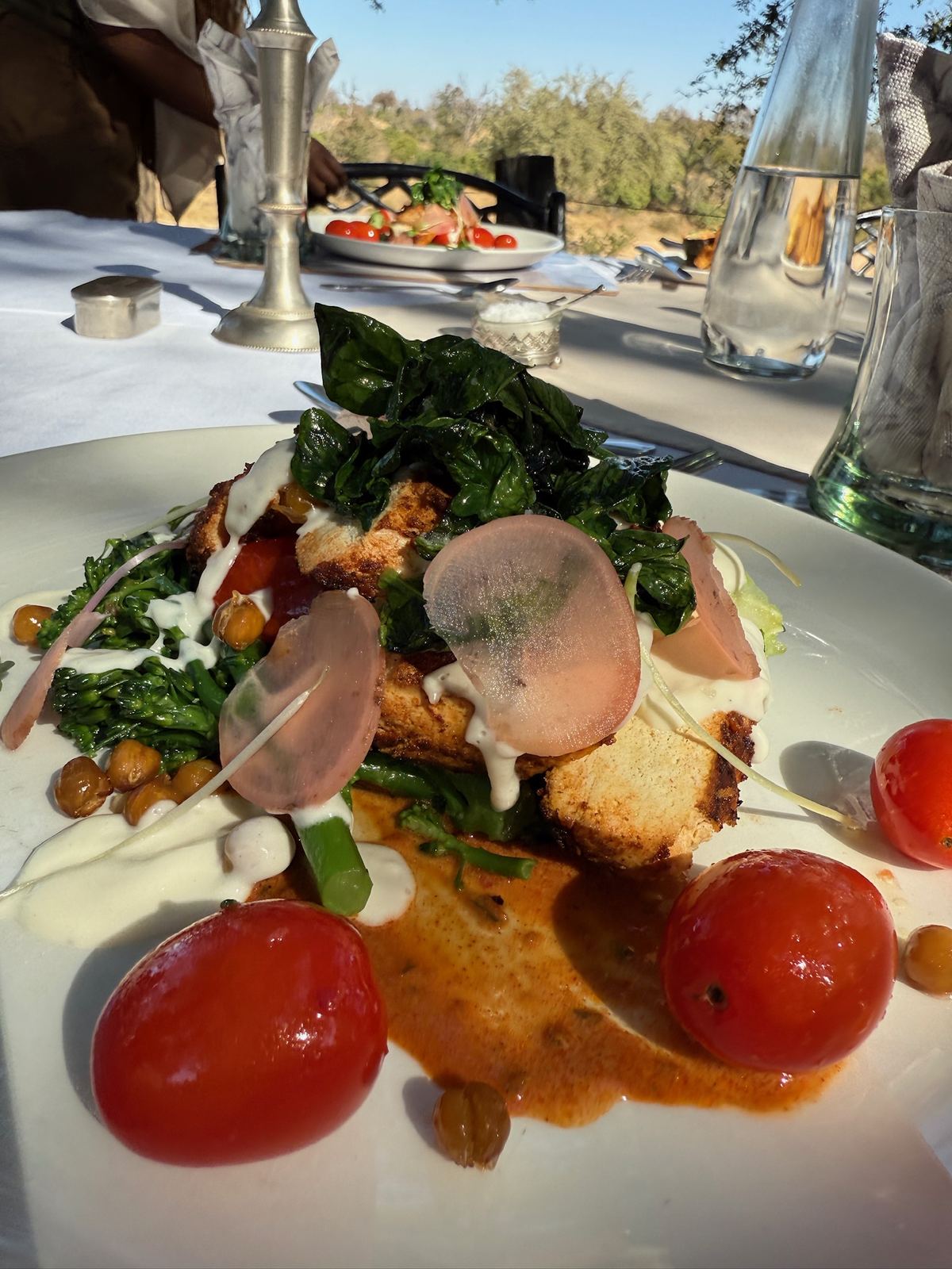 A plated vegan dinner with greens and roasted tomatoes at Kings Camp