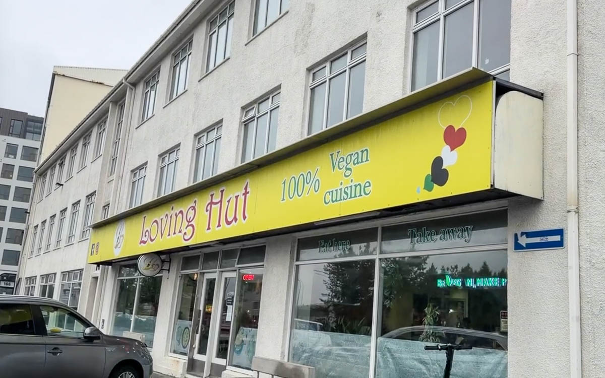 The yellow Loving Hut storefront in Reykjavík with a 100% vegan cuisine sign