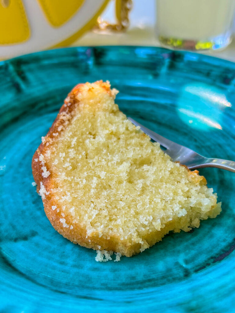 A slice of lemon cake on a bright blue plate.