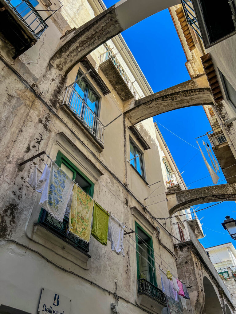 A narrow Amalfi alley with stone arches overhead and laundry hanging between the buildings.