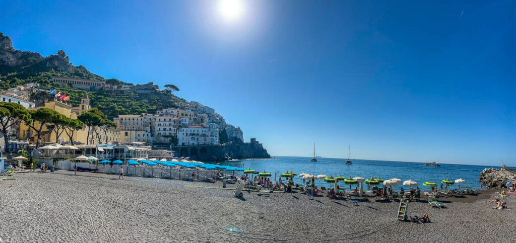 A wide view of the beach at Amalfi town with the hills behind it.