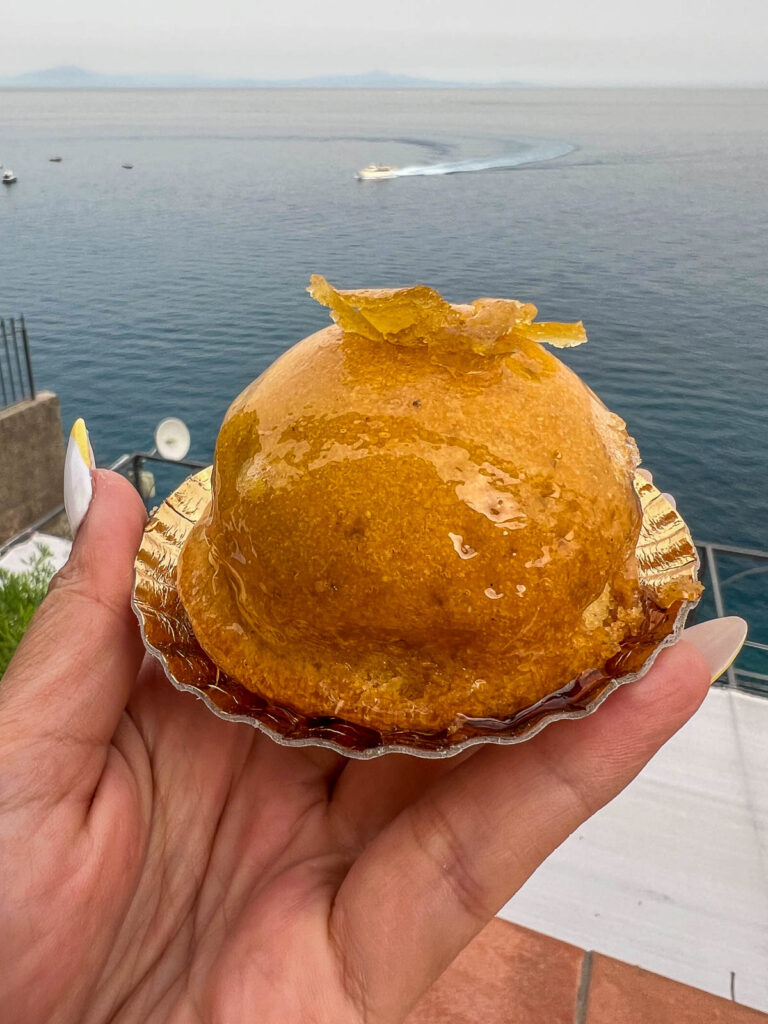 A dome-shaped lemon pastry held up over the sea in Minori.