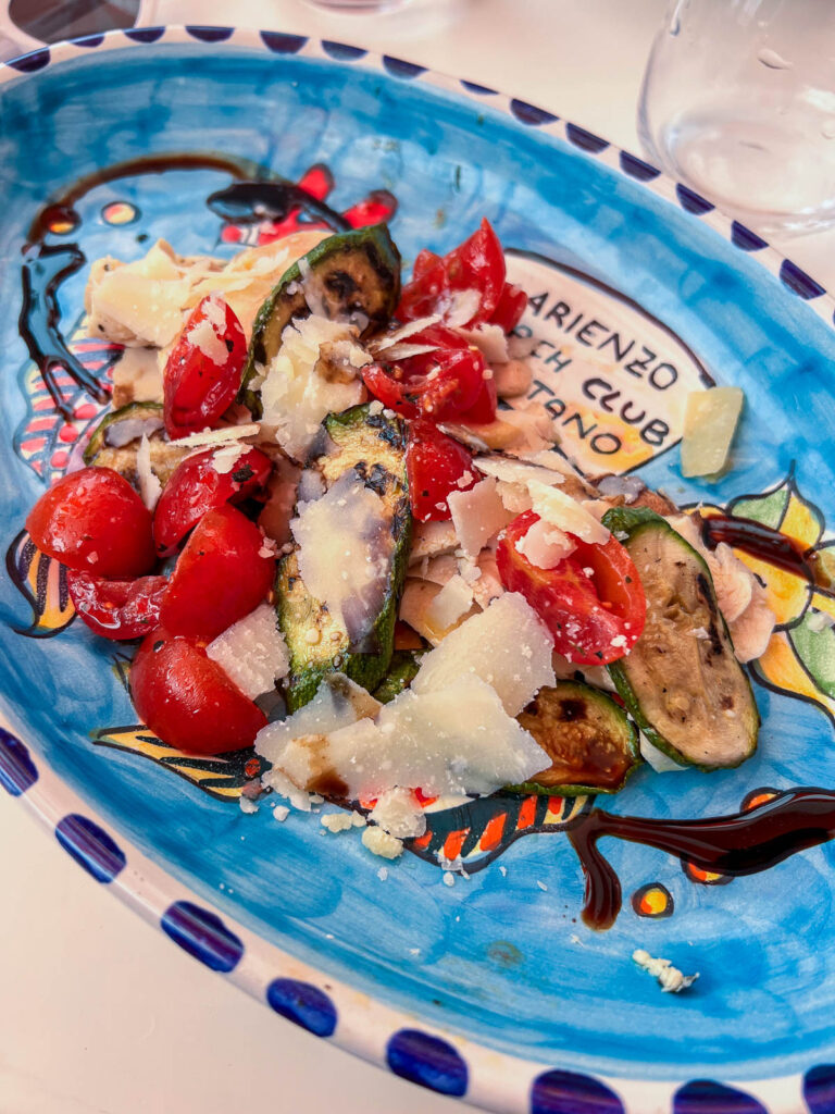 A seafood salad with tomatoes on a painted ceramic plate at Arienzo Beach Club.