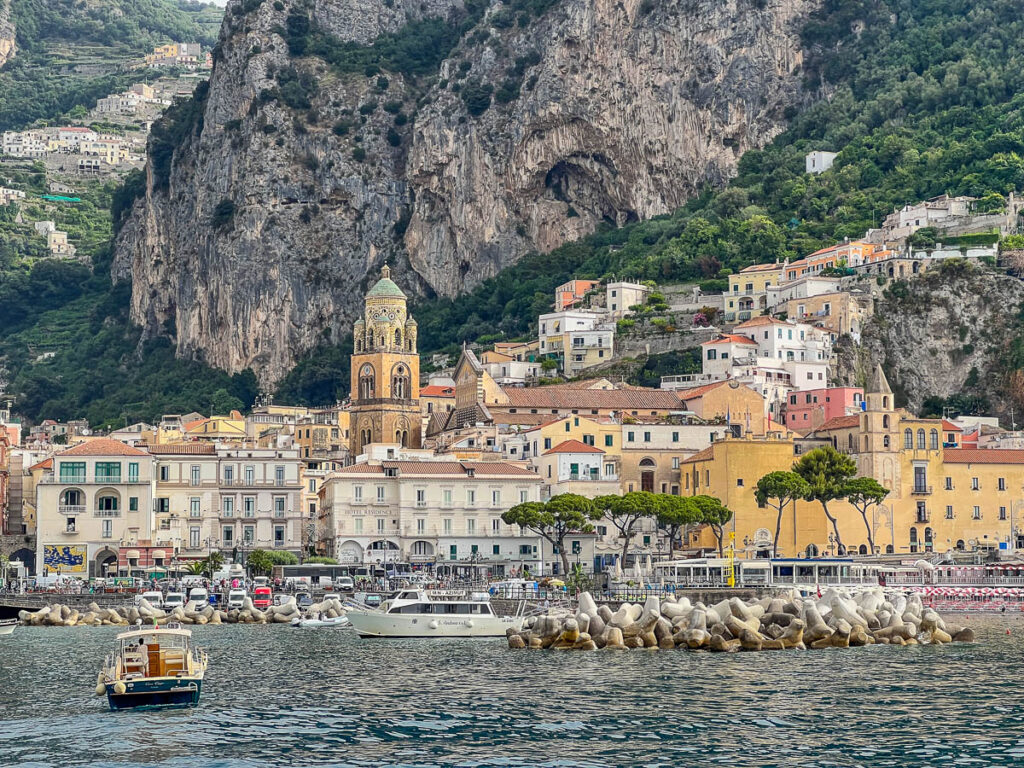 Amalfi town seen from the ferry, with the cathedral dome and cliffs behind it.