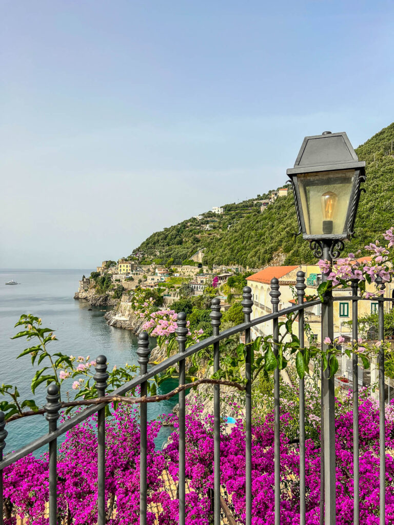 The view from our apartment terrace at Hotel Marmorata: an iron railing and lamp, pink bougainvillea, and the sea.