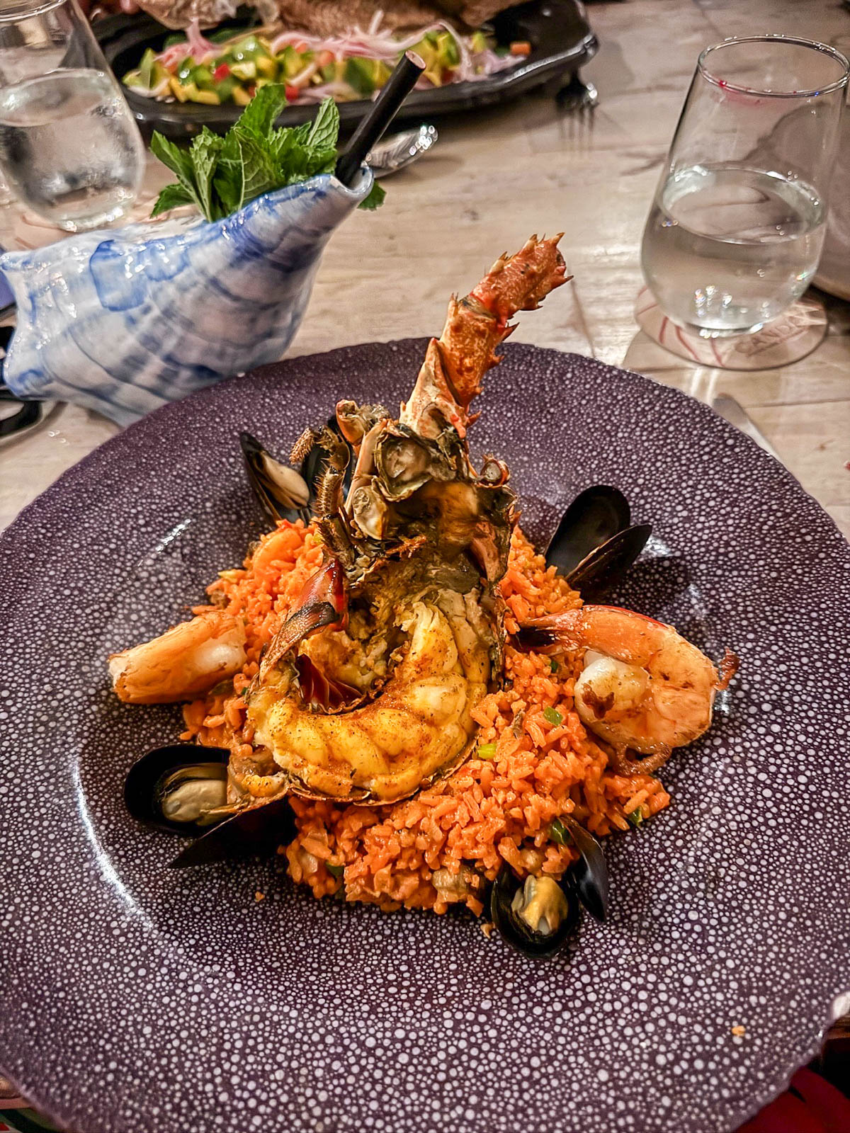 Plate of seafood rice topped with shrimp and mussels at Candé