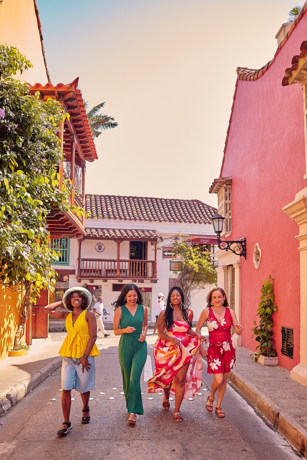 Four friends walking toward the camera down a colorful street in Cartagena's Old City