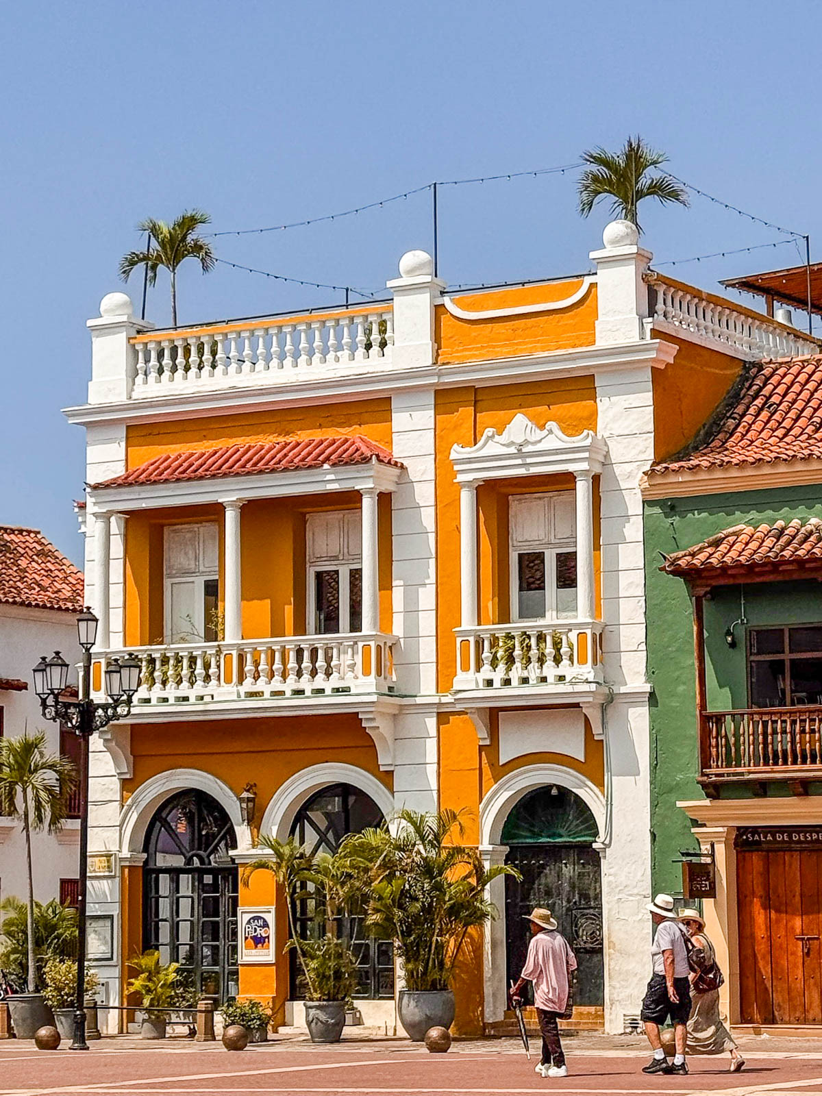 Bright orange and white colonial building with balconies and palm trees in Cartagena's Old City