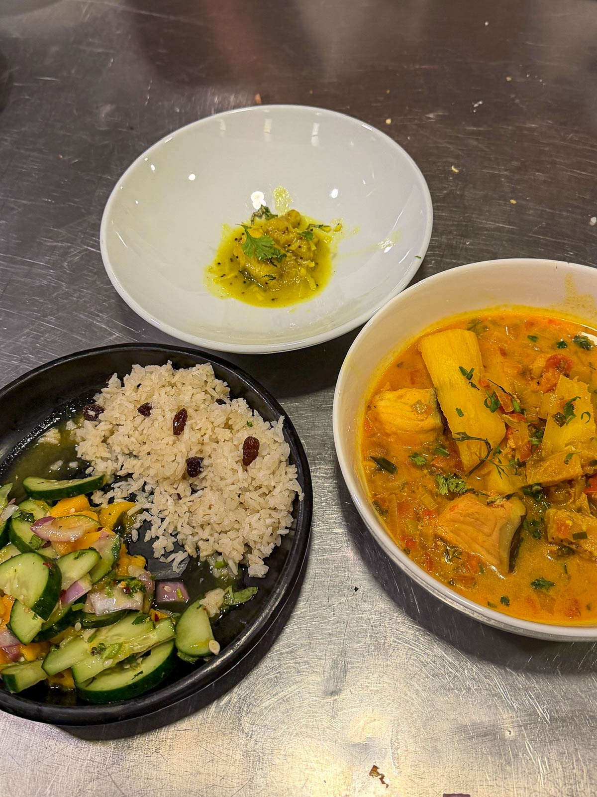 Finished cooking class dishes: rice, a cucumber salad, and a stew in bowls