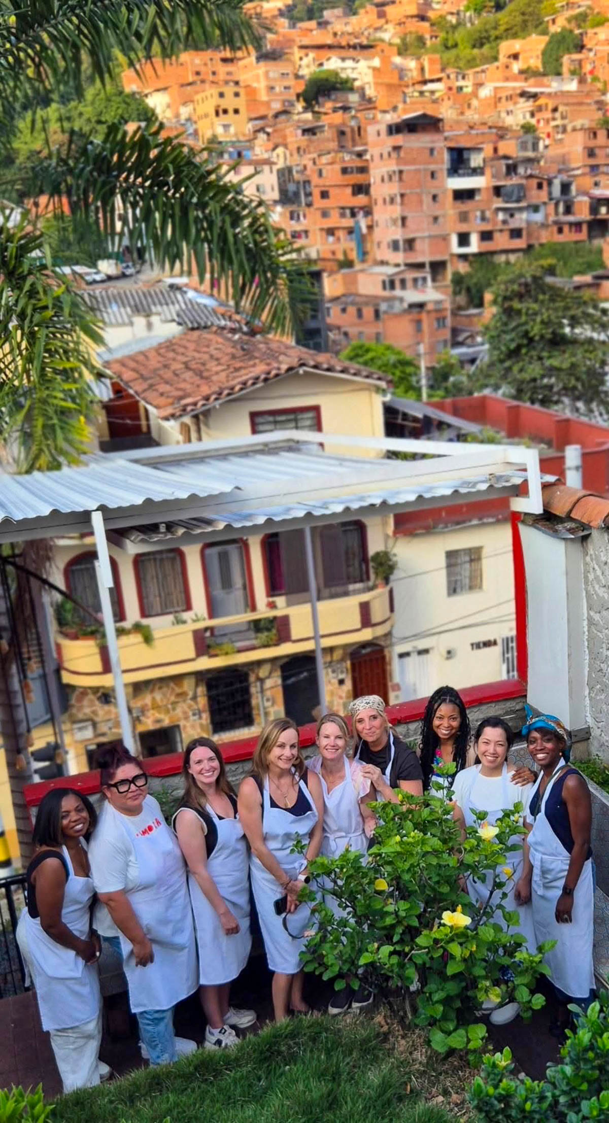 Our group in white aprons in front of hillside homes at our Medellín cooking class