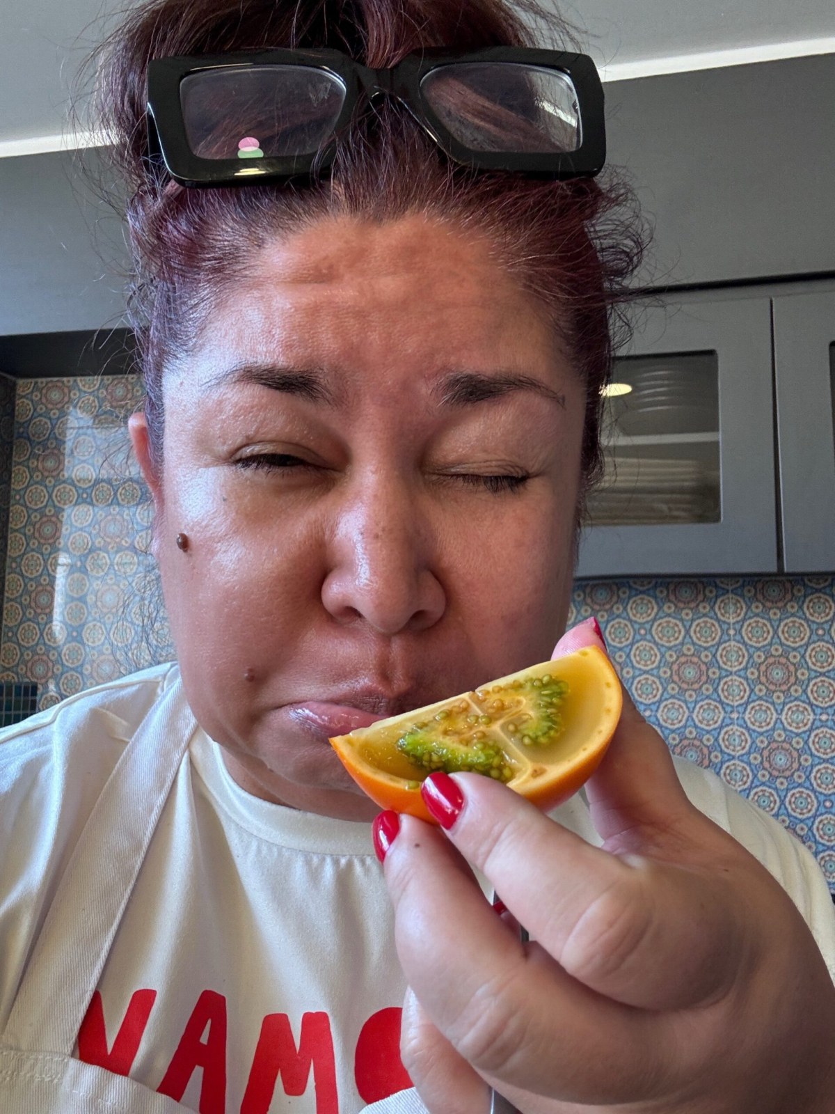 Cynthia making a sour face after biting into a lulo, a small orange fruit with a tart green inside, at our cooking class in Medellín