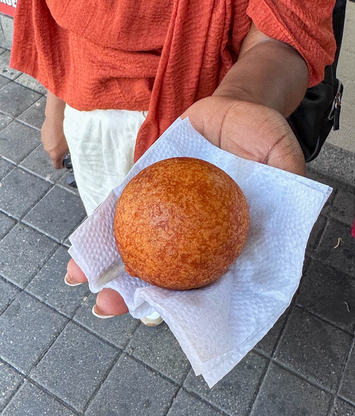 Hand holding a golden fried buñuelo on a napkin