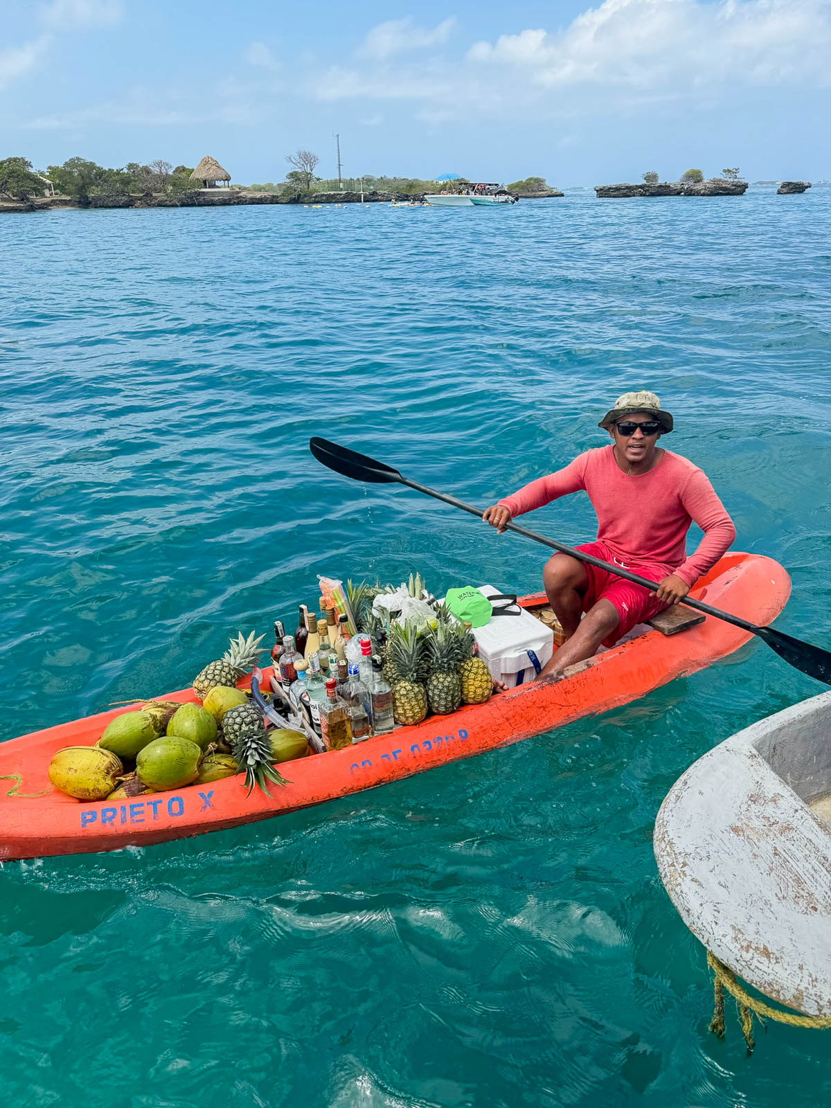 Fruit vendor paddling a kayak piled with fresh fruit in the Rosario Islands