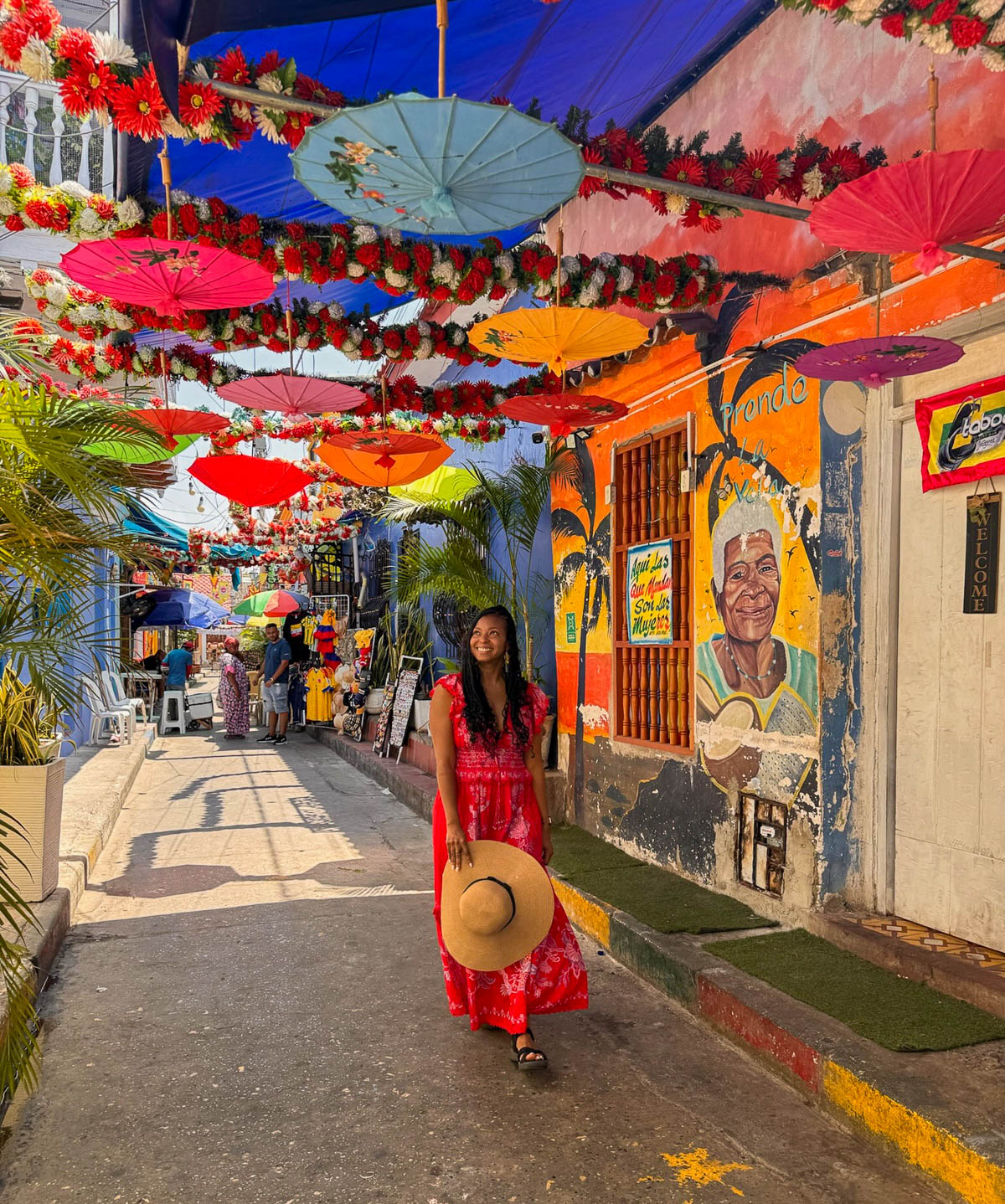Woman in a red dress walking under colorful umbrellas strung over a street in Getsemaní