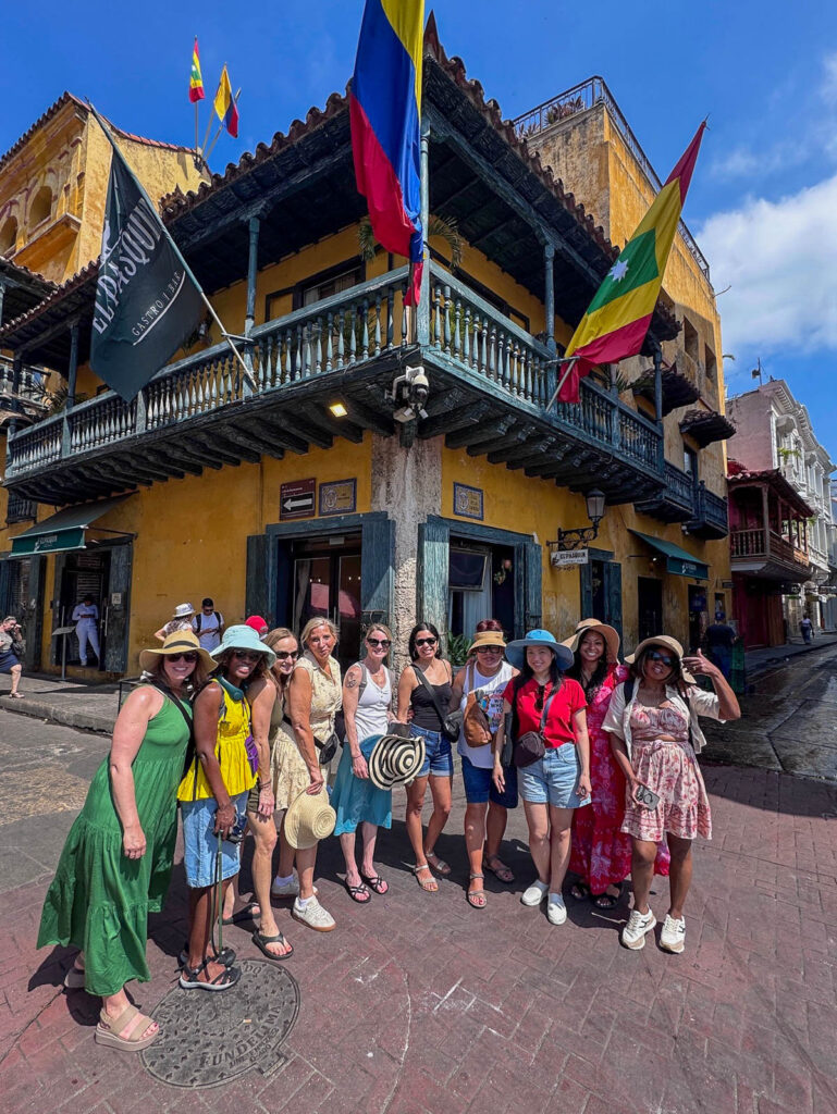 Our group gathered in front of a yellow colonial building hung with flags in Cartagena's Old City