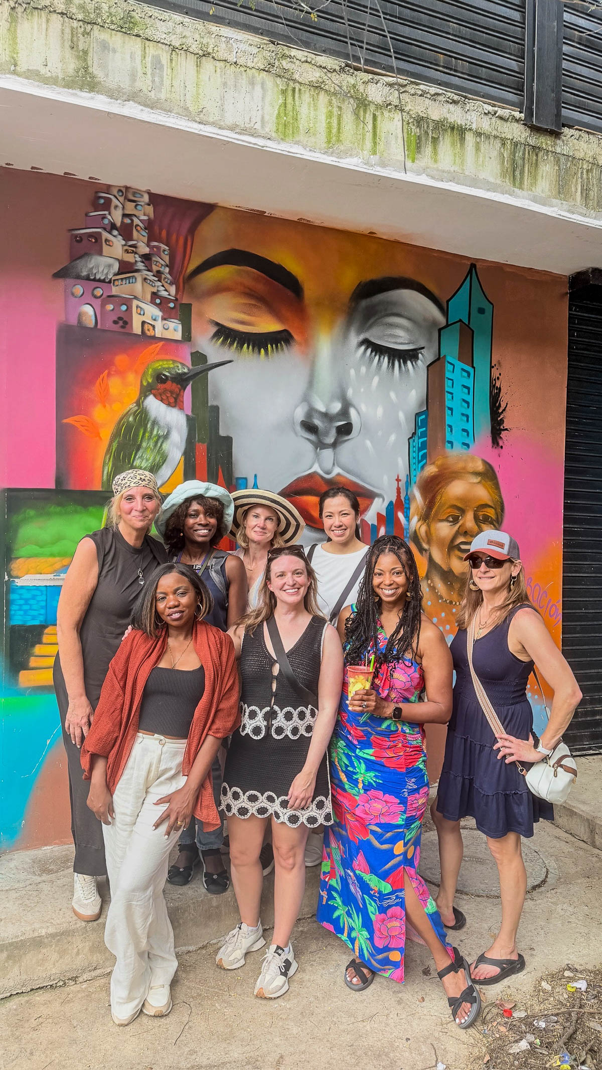 Our group posing in front of a colorful mural of a face in Comuna 13