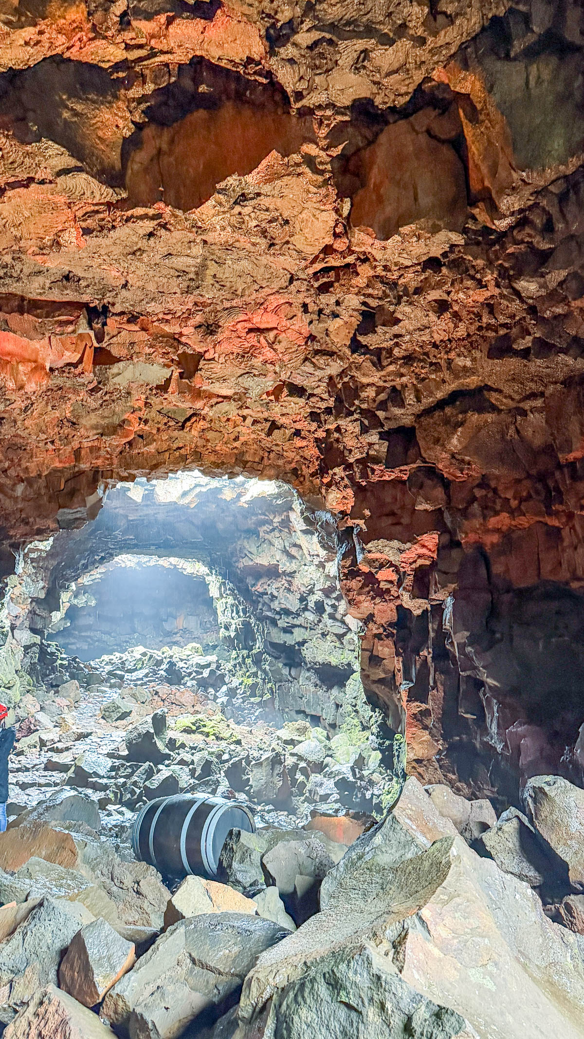 Inside Raufarhólshellir lava tunnel in Iceland, with red and orange rock walls