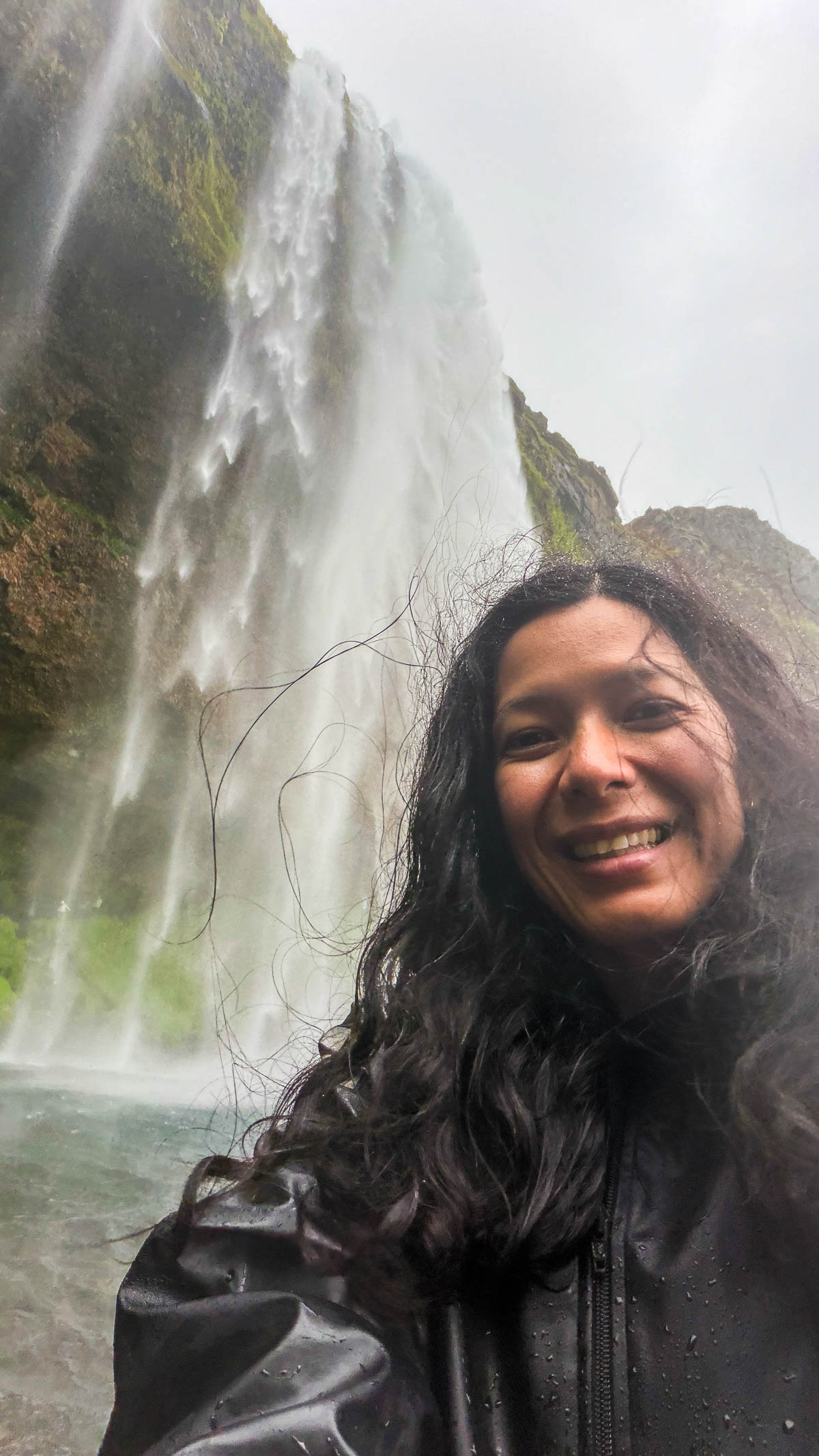 Toni taking a selfie beside the falling water at Seljalandsfoss