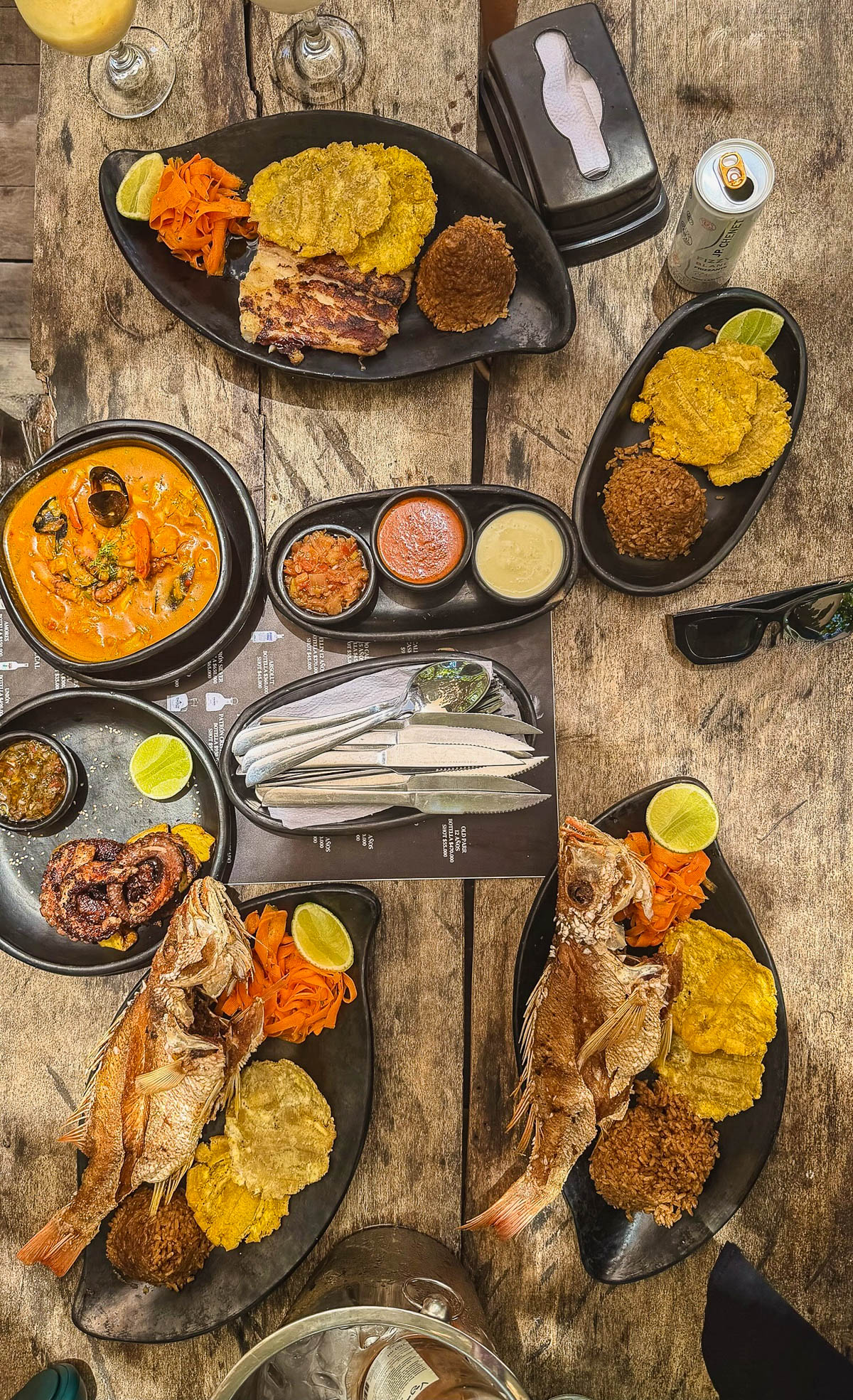 Island lunch of fried whole fish, patacones, and rice on a wooden table in the Rosario Islands
