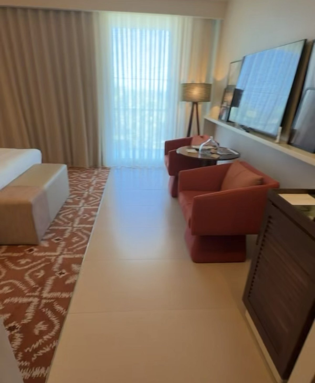 Sitting area with red armchairs and a TV in our ocean-view room at Kimpton Atlântico Algarve