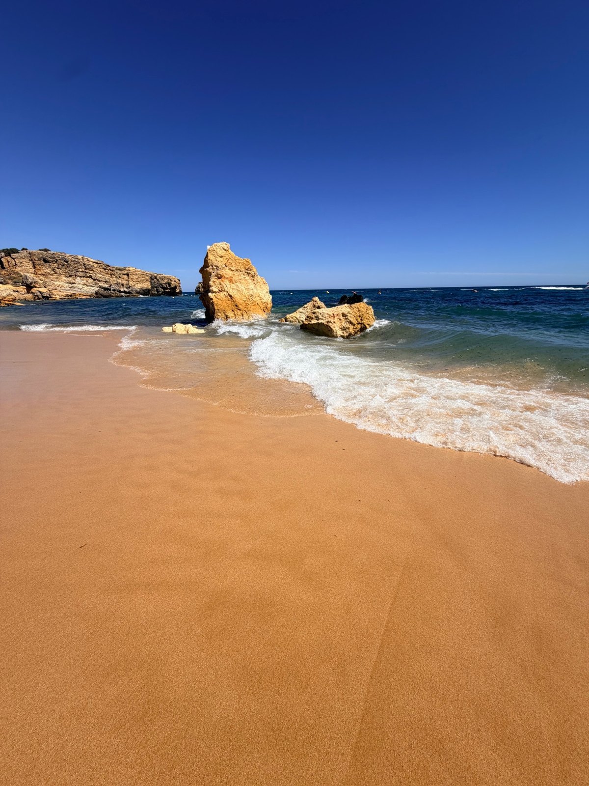 Waves washing around a large rock on São Rafael Beach in the Algarve