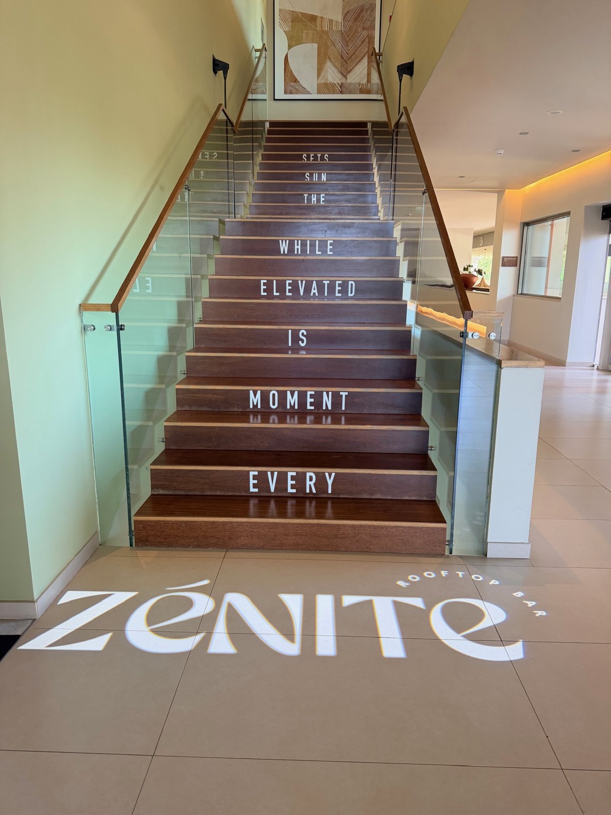 Stairs leading up to Zénite Rooftop with the logo projected on the floor at Kimpton Atlântico Algarve