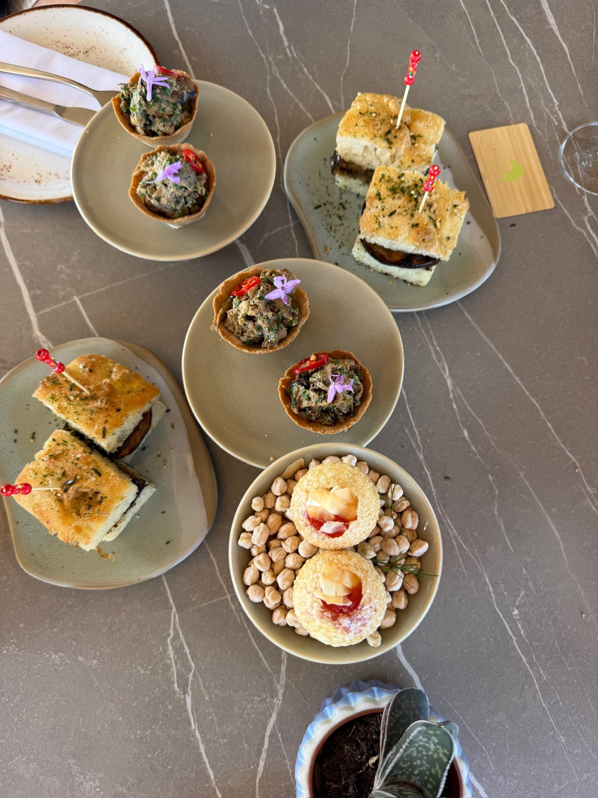 Overhead view of vegan tapas at Zénite Rooftop with focaccia sandwiches, mushroom cups, and chickpea puffs