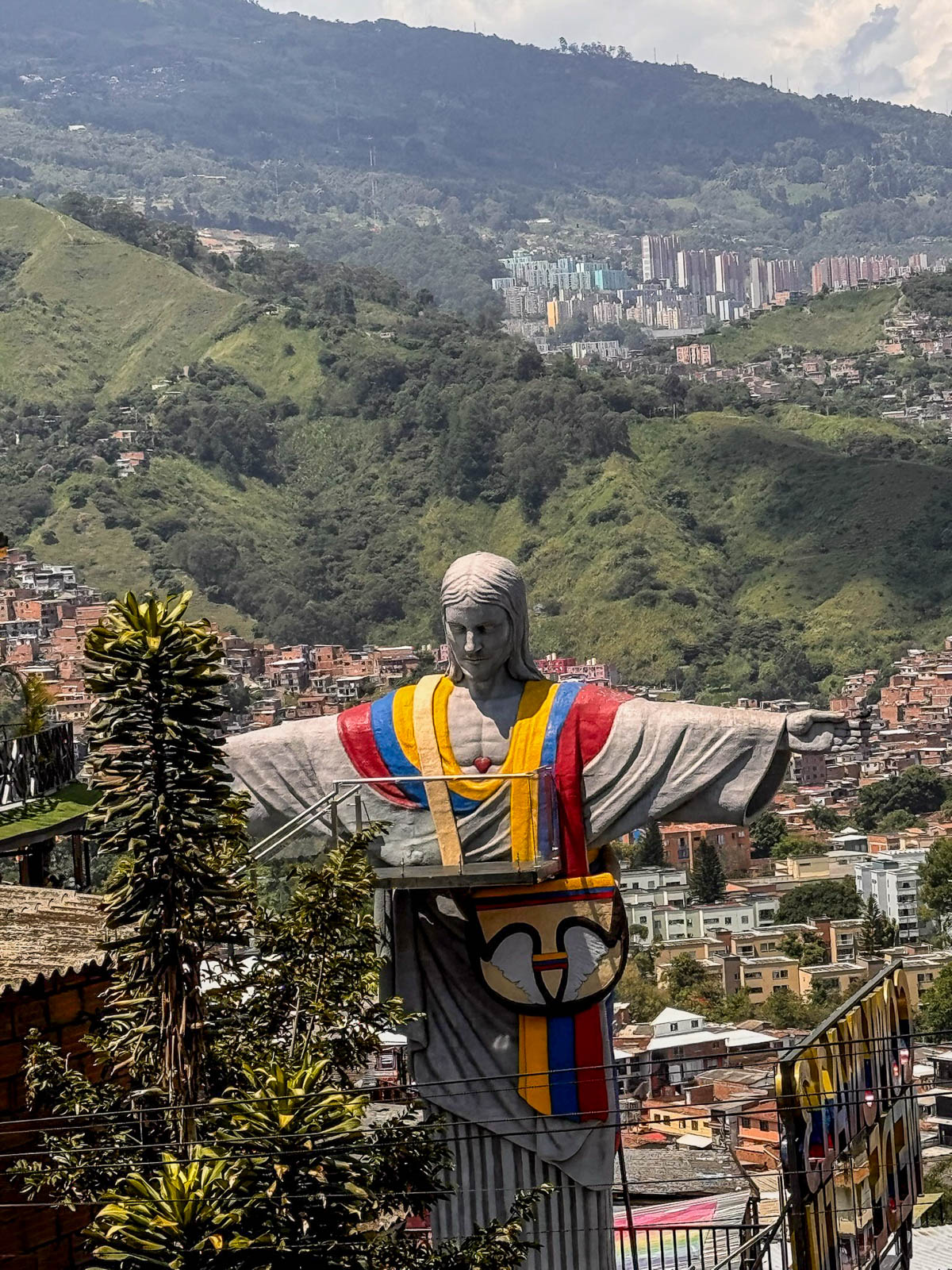 Statue painted in the colors of the Colombian flag overlooking the green Medellín valley