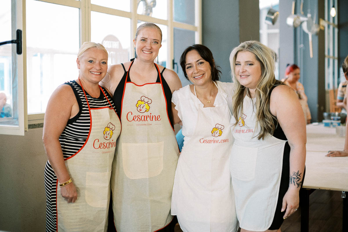 Four travelers in Cesarine aprons smiling at the cooking class