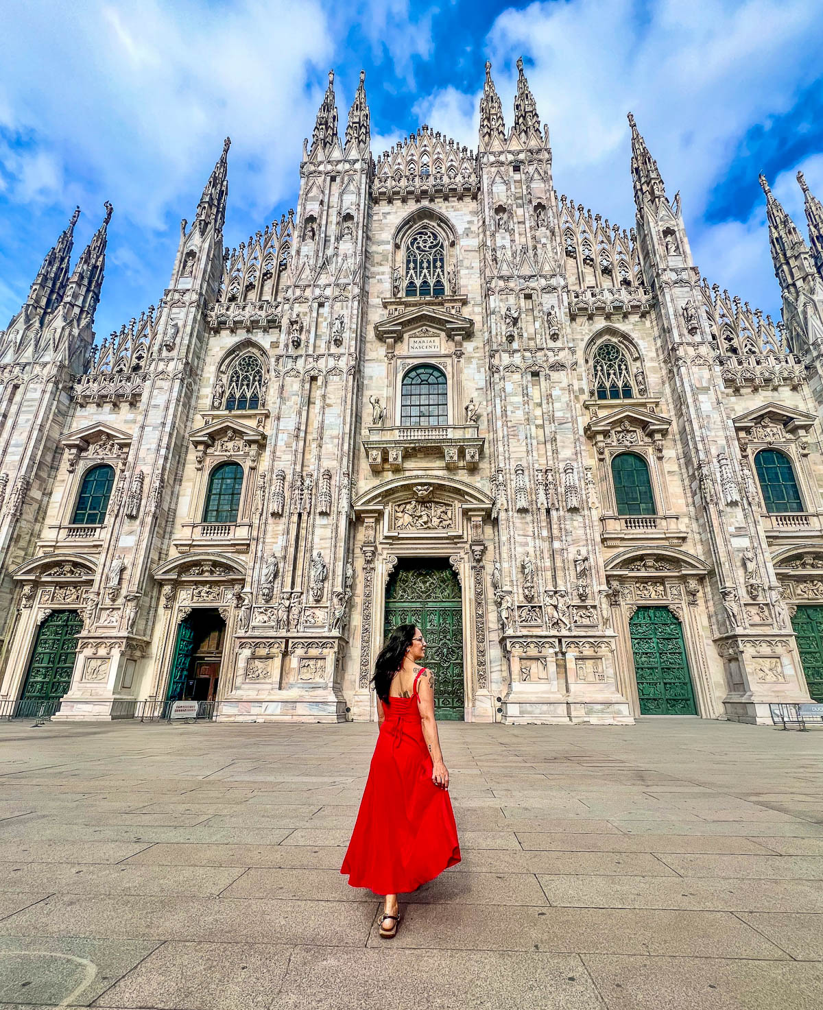 A traveler in a red dress standing in front of the Milan Duomo