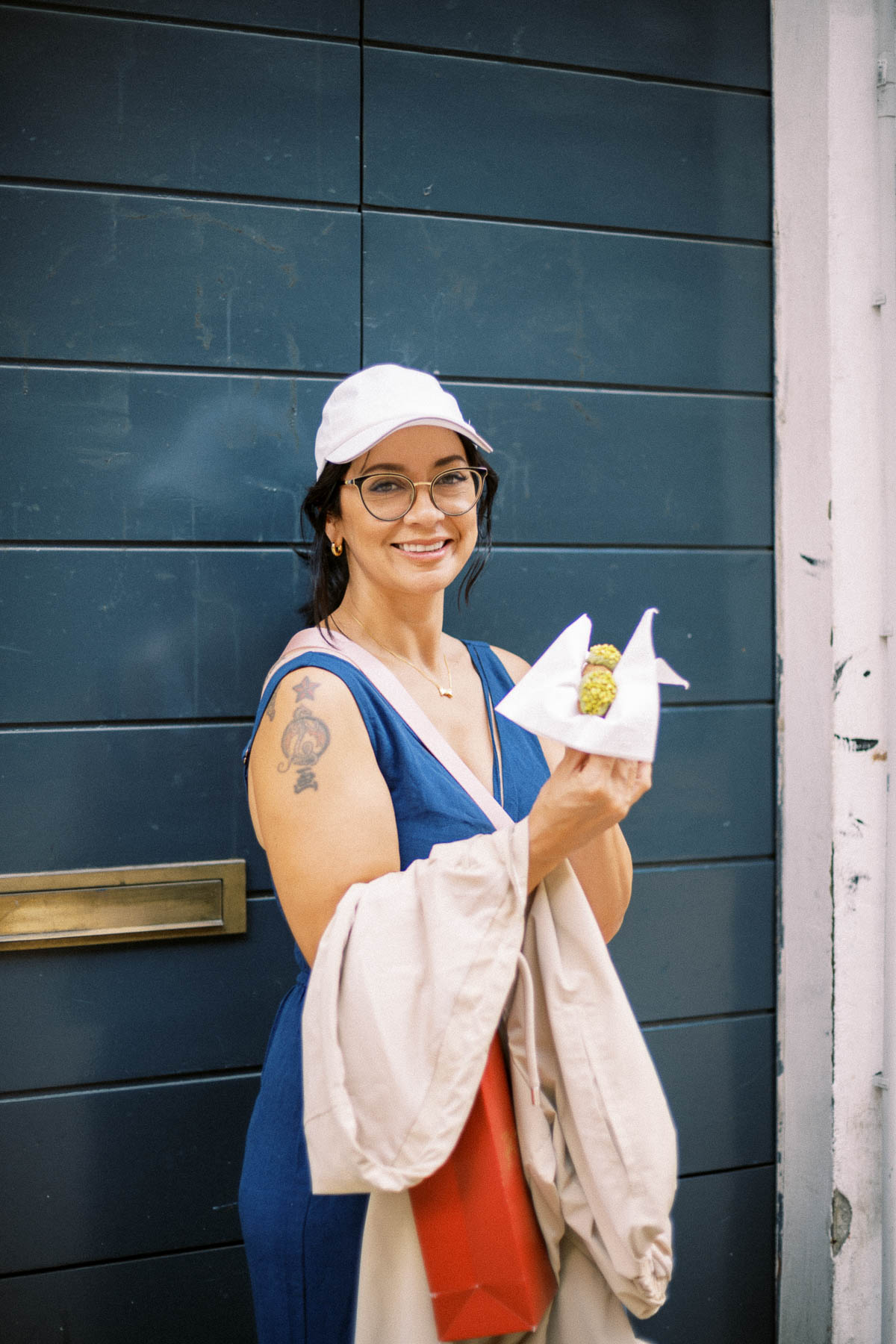 A traveler holding a pistachio cannoli in front of a blue door in Milan