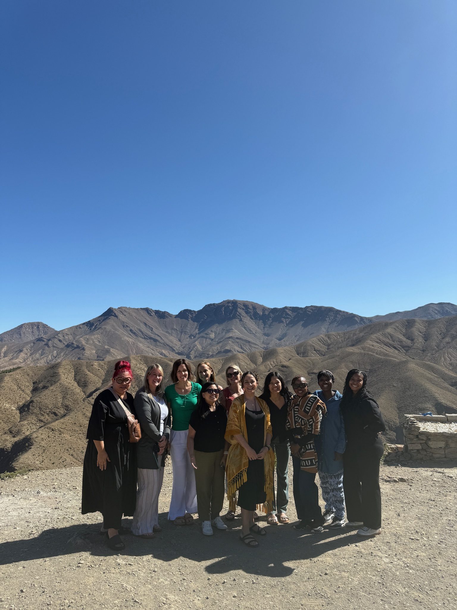 A group of women posing together at a viewpoint over the Atlas Mountains