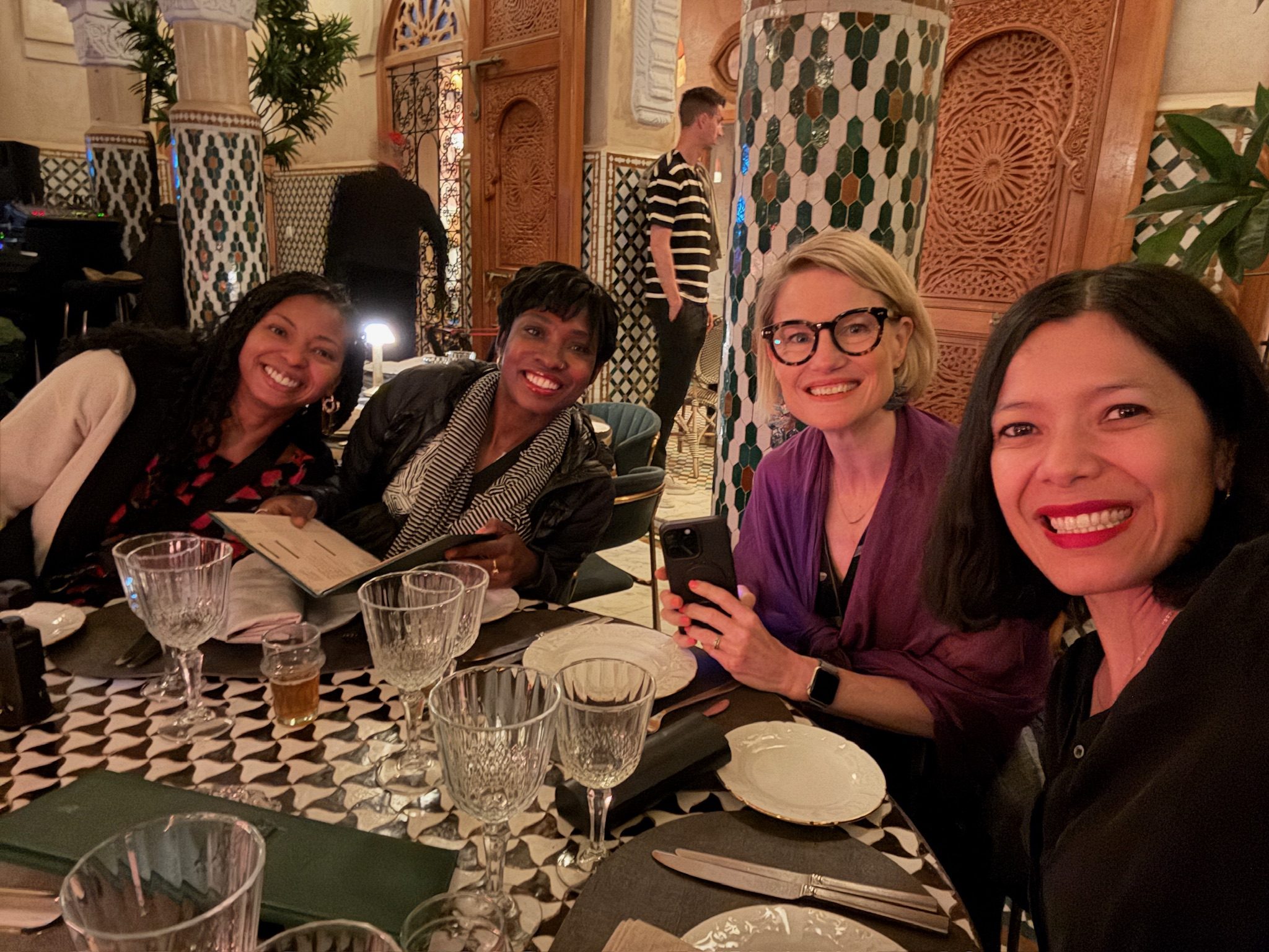 Four women smiling at a dinner table in the tiled dining room at Dar Dada